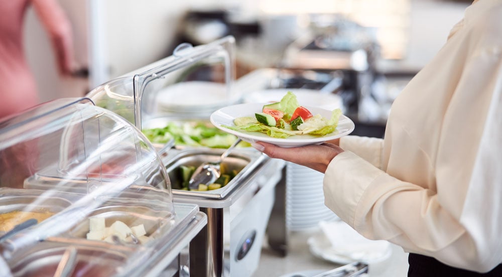 Mulher se servindo em restaurante self-service, onde irá pagar com o Cartão FLEX da Sem Parar Empresas