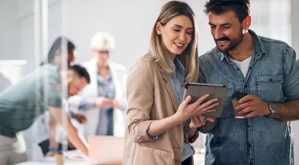 Sem Parar Empresas: mulher, gestora de RH, mostrando para um colaborador os benefícios na empresa na tela de um tablet 