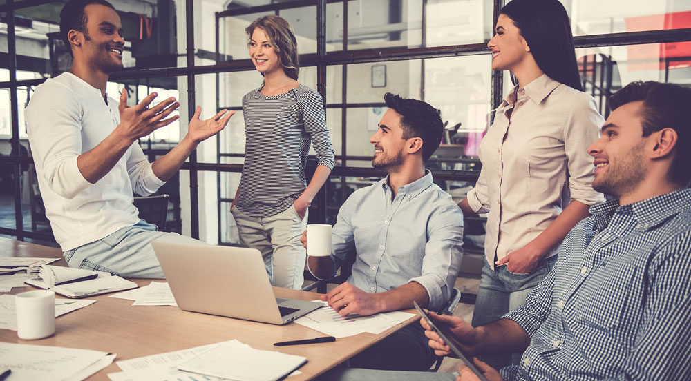 Sem Parar Empresas: cinco pessoas em escritório sorrindo e conversando sobre a construção de uma boa marca empregadora