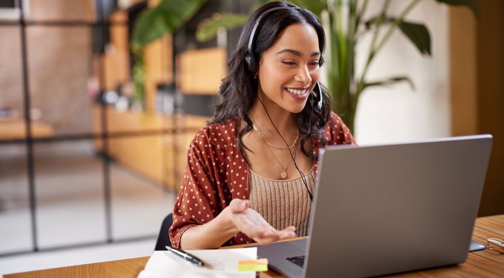 Mulher sorrindo em frente a um notebook analisando os tipos de benefícios Sem Parar Empresas