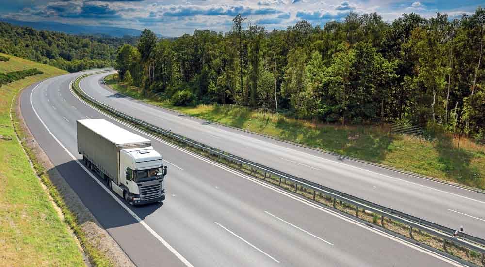 Sem Parar Empresas: caminhão sob Inventário de emissões rodando em estrada arborizada