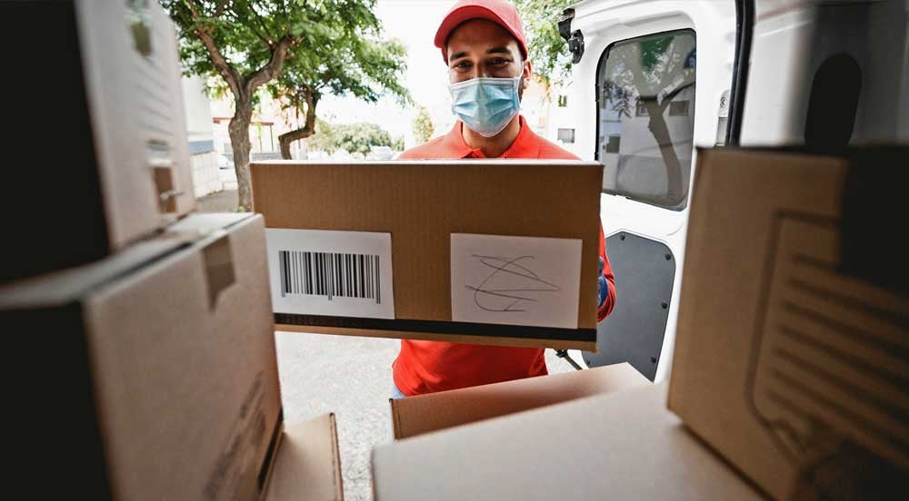 Sem Parar Empresas: homem de máscara retirando pacote de van que está fazendo logística pós-pandemia
