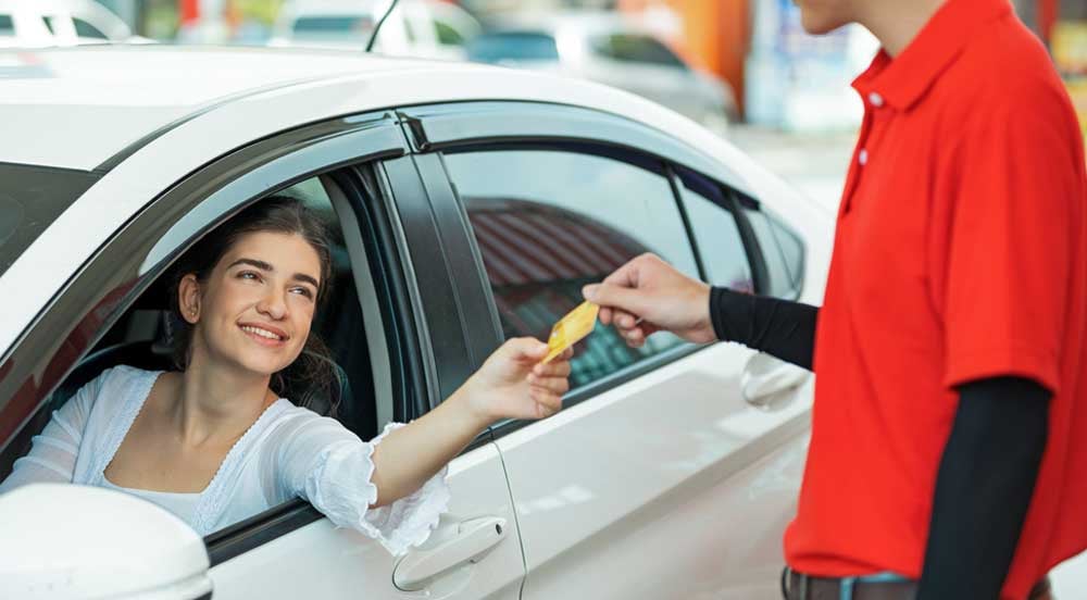 Sem Parar Empresas: mulher pagando frentista que possui boa abordagem ao cliente no posto de gasolina