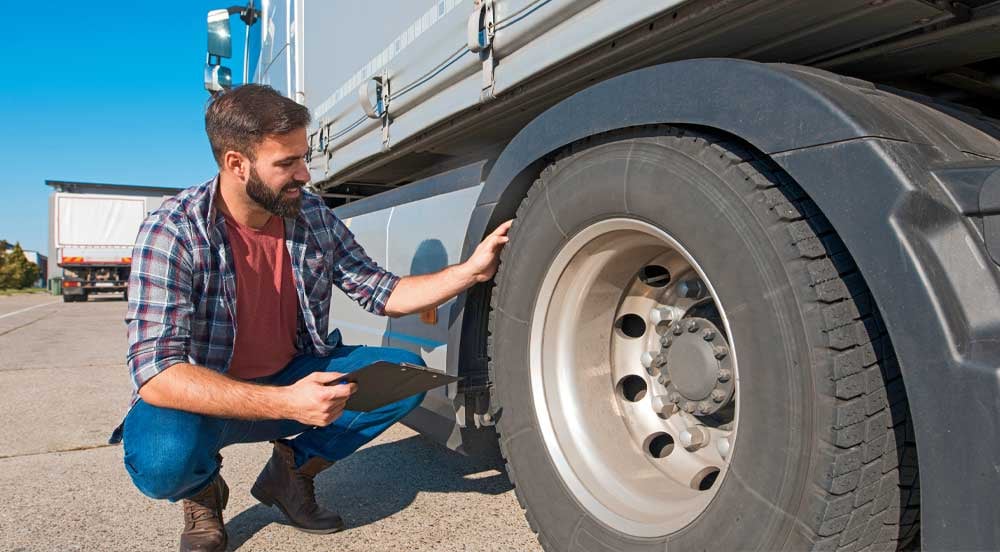 Sem Parar Empresas: homem analisando pneu de caminhão para fazer cálculo de depreciação de veículo