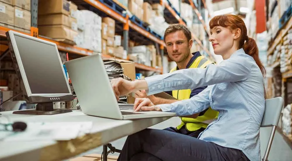 Sem Parar Empresas: homem e mulher em um armazém de produtos fazendo os relatórios gerenciais na logística