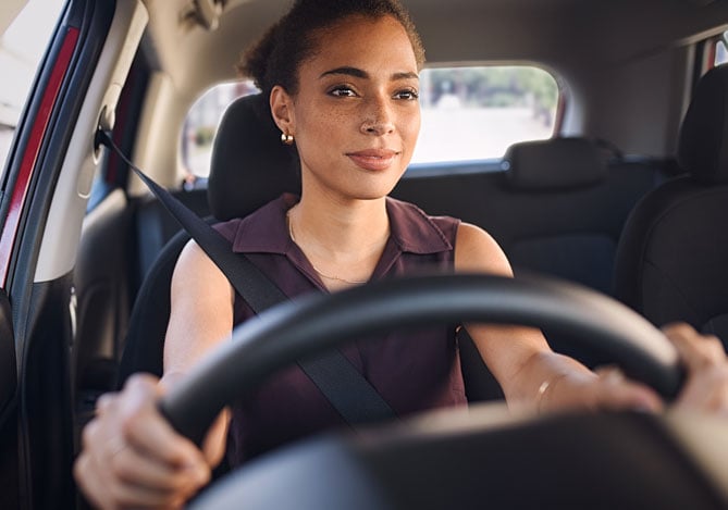 Sem Parar Empresas: interior de um carro com uma mulher dirigindo atentamente para calcular consumo de combustível