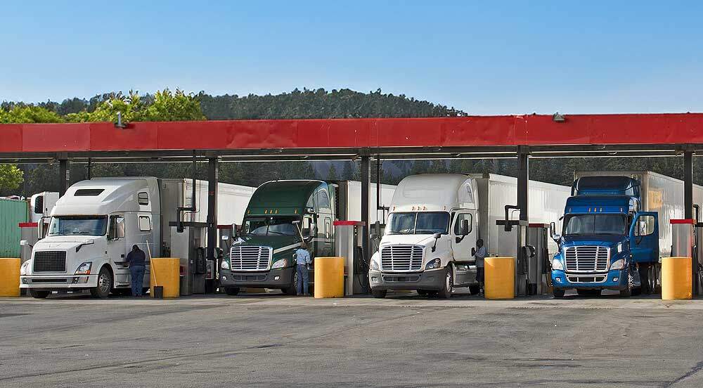 Cinco caminhões enfileirados em posto para abastecer com o sistema de controle de combustível frota Sem Parar Empresas