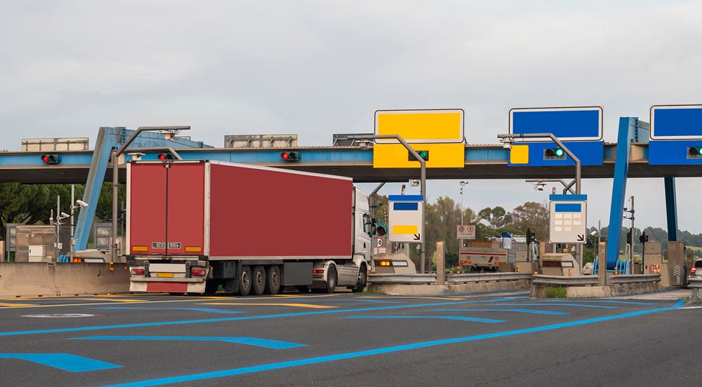 Praça de cobrança em rodovia com um veículo de carga passando pela cobrança automática com a tag pedágio para caminhão Sem Parar Empresas