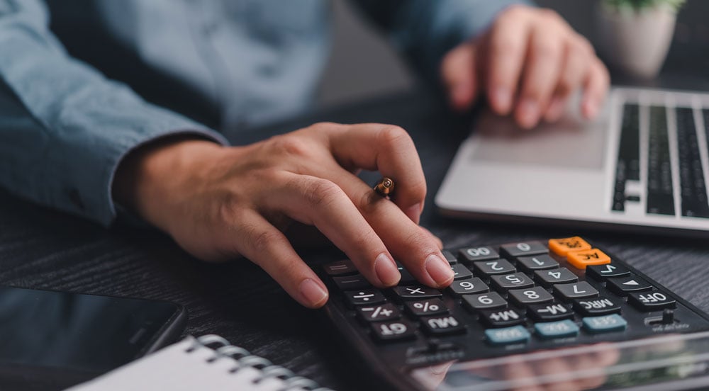 Sem Parar Empresas: mãos mexendo em calculadora e notebook para encontrar a média de consumo de combustível da sua frota