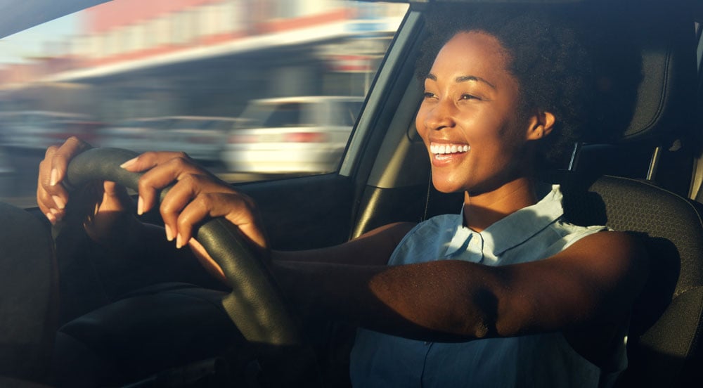 Sem Parar Empresas: Mulher sorrindo e dirigindo um carro para fazer visita comercial