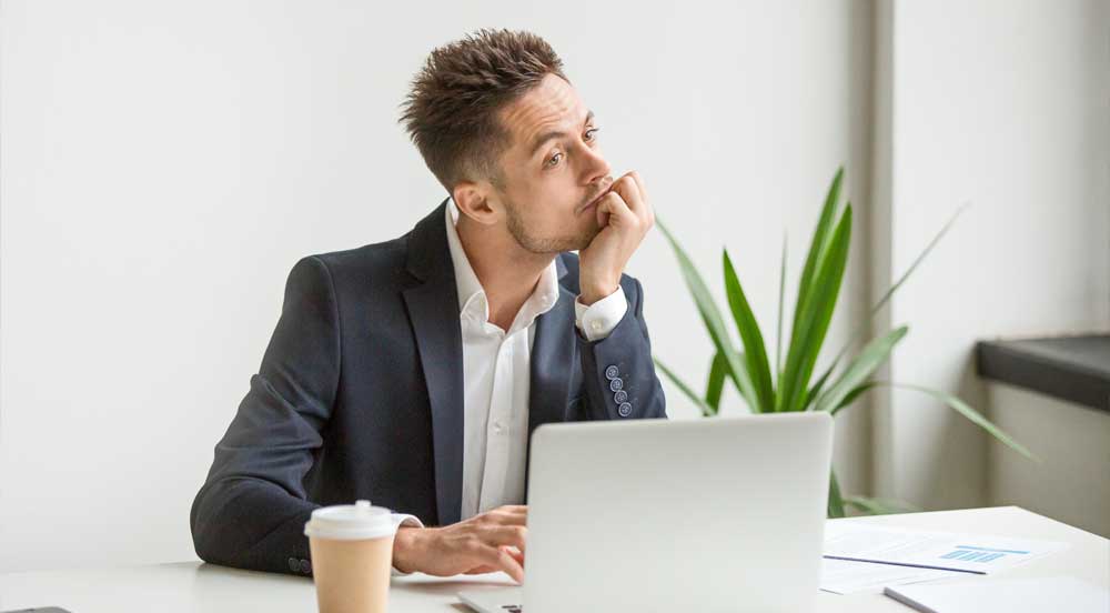 Sem Parar Empresas: homem em frente ao notebook com aspecto cansado, sendo uma das causas do absenteísmo