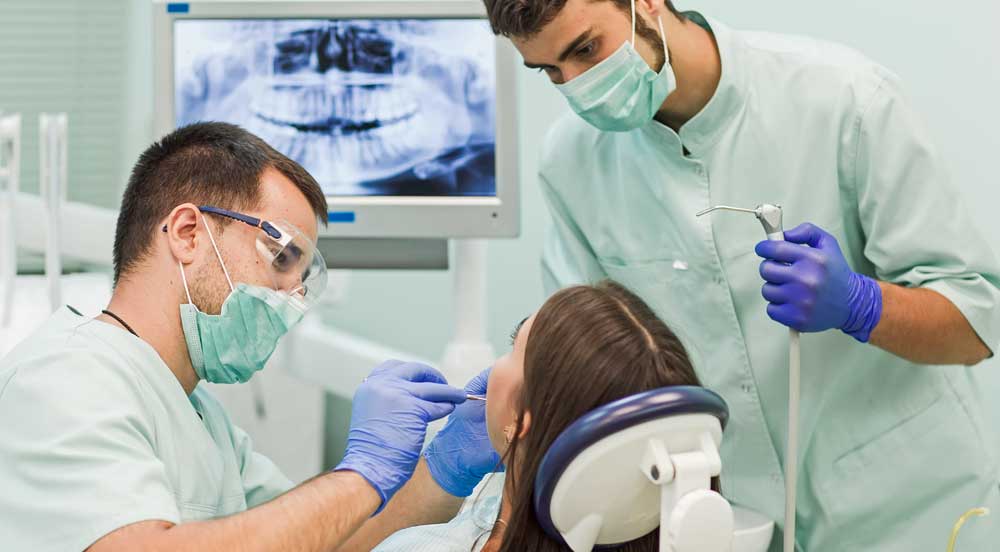 Sem Parar Empresas: dois dentistas atendendo uma paciente que possui convênio odontológico