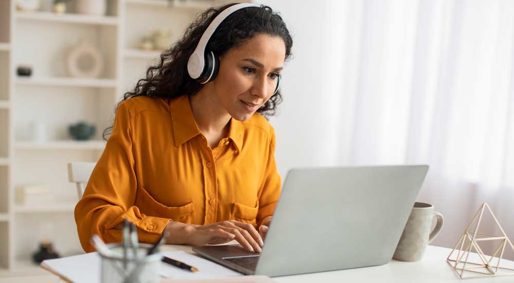 Sem Parar Empresas: mulher de fone de ouvido olhando para o notebook enquanto está cursando e-learning