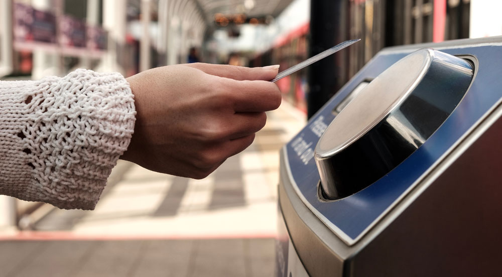Mão aproximando o cartão transporte Sem Parar Empresas ao leitor de pagamento de metrô