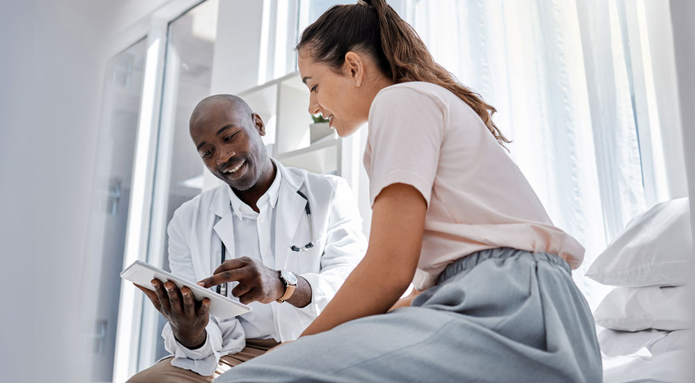 Sem Parar Empresas: médico mostrando a tela de um tablet para a paciente que utiliza plano de saúde empresarial
