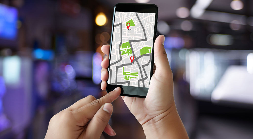 Mãos segurando um celular aberto no aplicativo do Mapa para traçar uma boa rota para o trabalho com a ajuda da Sem Parar Empresas