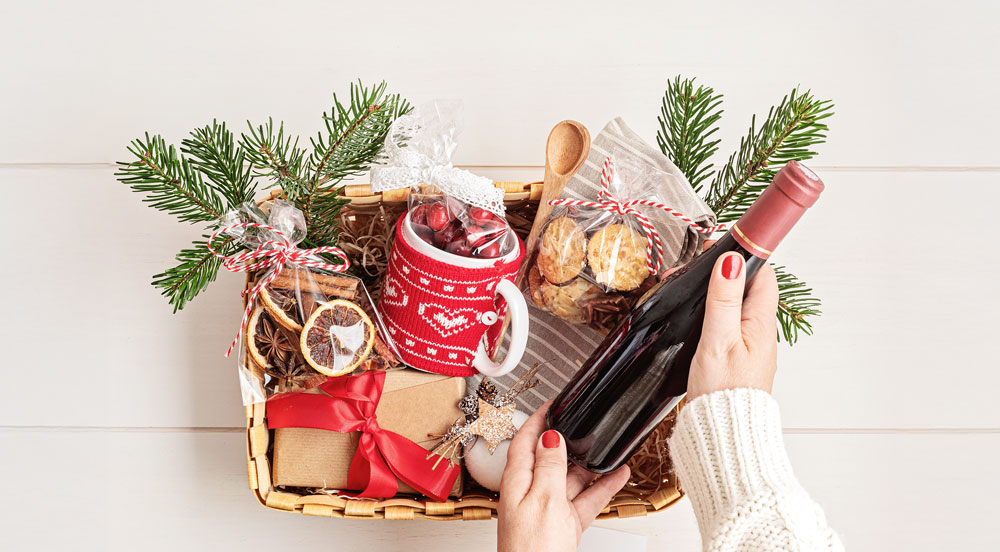 Sem Parar Empresas: mãos femininas colocando um vinho dentro da cesta de Natal para empresas