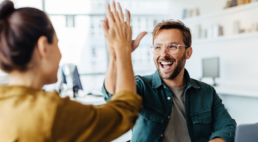 Sem Parar Empresas: pessoas em um escritório, felizes, batendo as mãos e sorrindo, pois possuem boas condições de  trabalho e saúde mental