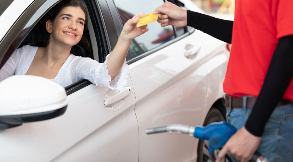 Sem Parar Empresas: mulher em carro entregando o cartão para o frentista do posto para prosseguir com o vale-combustível: como funciona aos funcionários