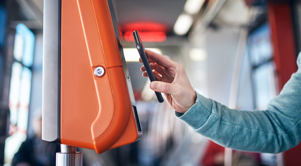 Sem Parar Empresas: pessoa aproximando o celular do leitor do ônibus para pagar a passagem por meio do vale-transporte digital