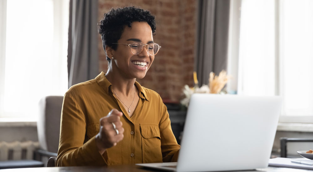 Sem Parar Empresas: mulher em home office muito feliz em frente ao seu computador