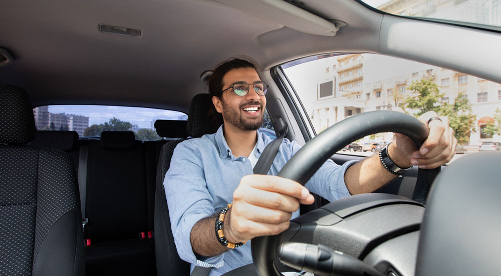 Sem Parar Empresas: homem sorrindo enquanto dirige um carro em viagem de negócios