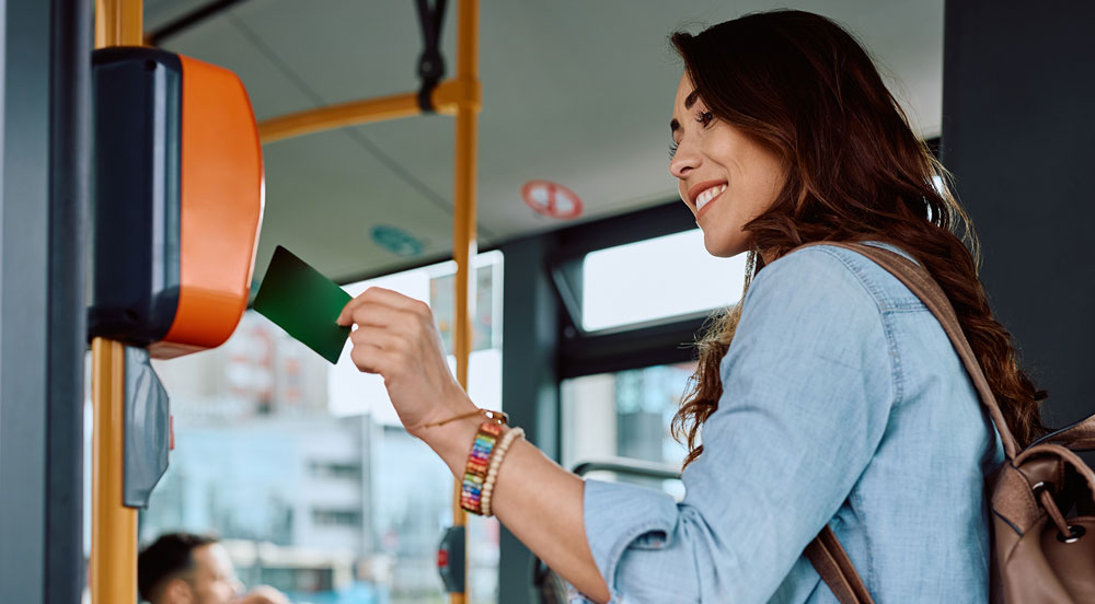 Sem Parar Empresas: mulher aproximando cartão para passar na catraca do ônibus, benefício garantido pela lei do vale-transporte