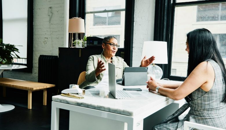 Sem Parar Empresas: duas mulheres, sendo uma gestora e outra colaboradora, sentadas frente a frente em uma mesa de escritório para debater sobre como calcular férias vendidas