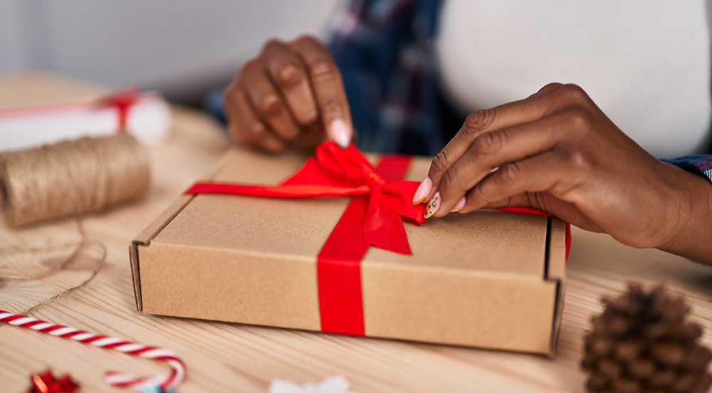 Sem Parar Empresas: mãos apertando um laço vermelho que envolve um presente de Natal corporativo