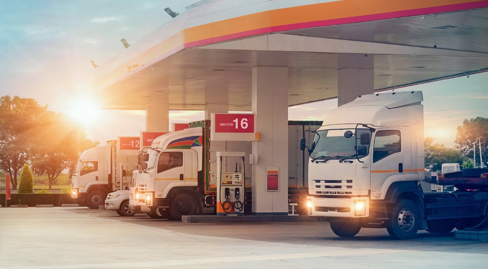 Sem Parar Empresas: três caminhões em posto de gasolina representando o abastecimento externo