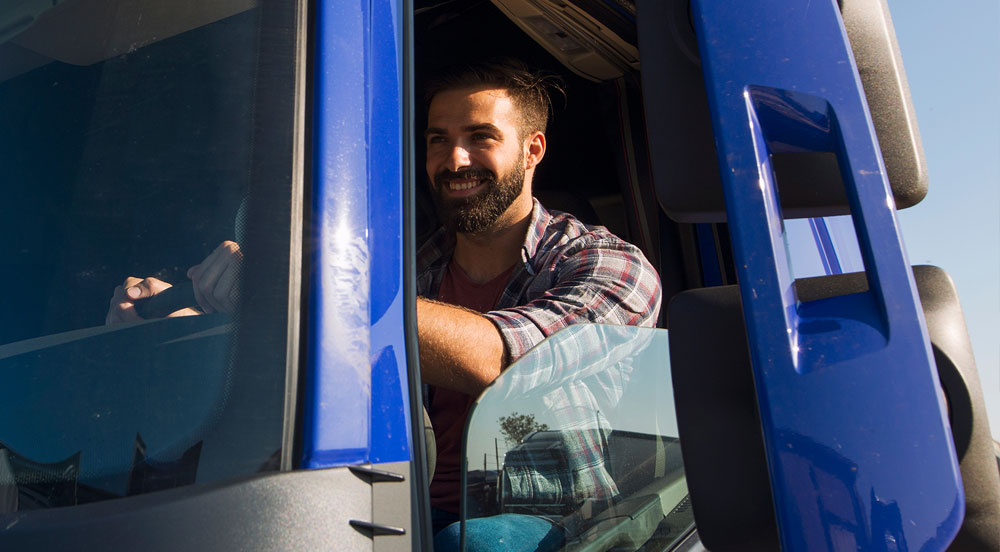 Homem dirigindo um caminhão azul que recebeu o Vale-Pedágio Sem Parar Empresas