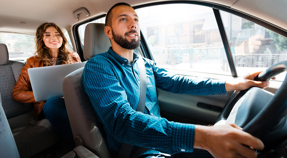 Sem Parar Empresas: homem dirigindo um carro e mulher no banco de trás, pois ele possui MEI para motorista de aplicativo