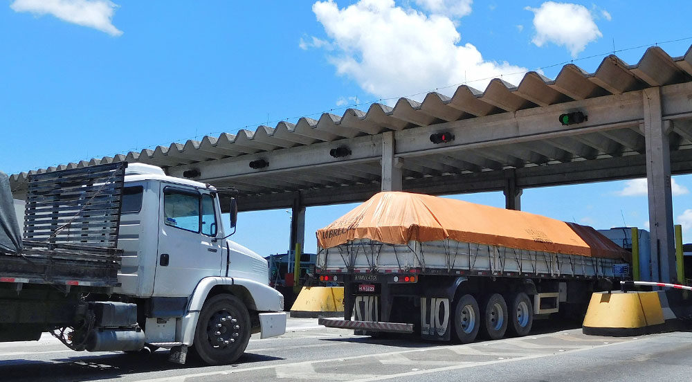Sem Parar Empresas: caminhões passando pela cobrança de pedágio sobre eixo suspenso em uma rodovia