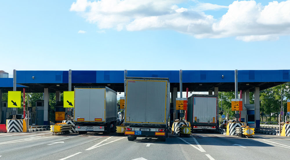 Praça de cobrança em rodovia com vários caminhões representando como adquirir o vale-pedágio Sem Parar Empresas