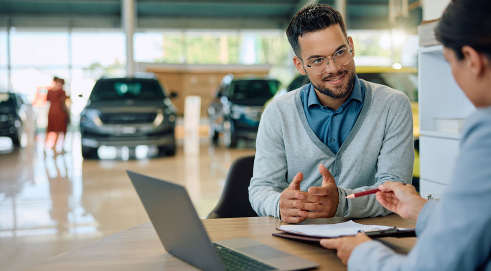 Sem Parar Empresas: homem conversando com vendedora em concessionária para comprar carro com CNPJ