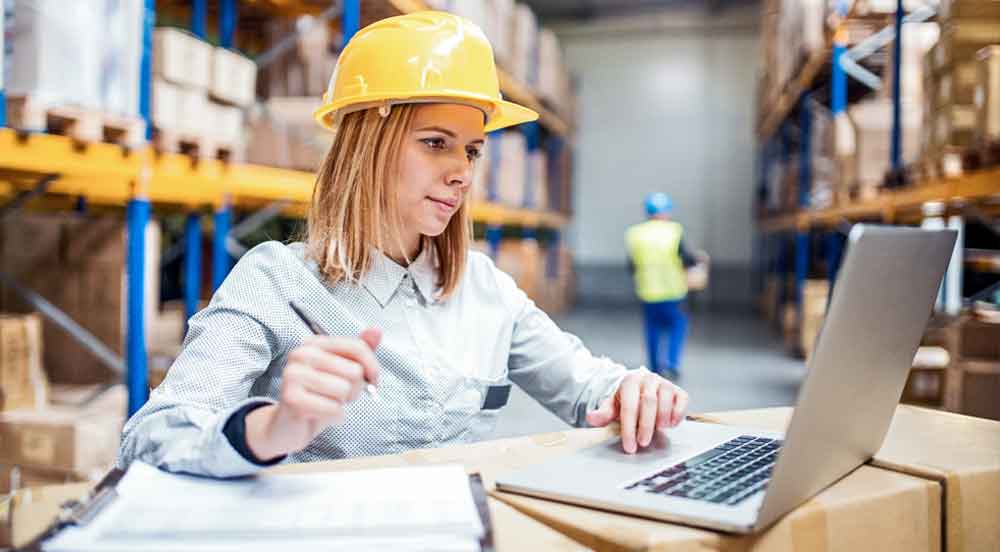 Sem Parar Empresas: mulher olhando notebook em estoque para fazer o planejamento da logística de transporte