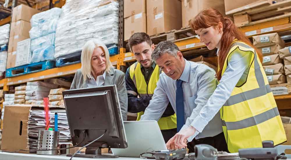 Sem Parar Empresas: quatro pessoas em armazém fazendo a auditoria de frete
