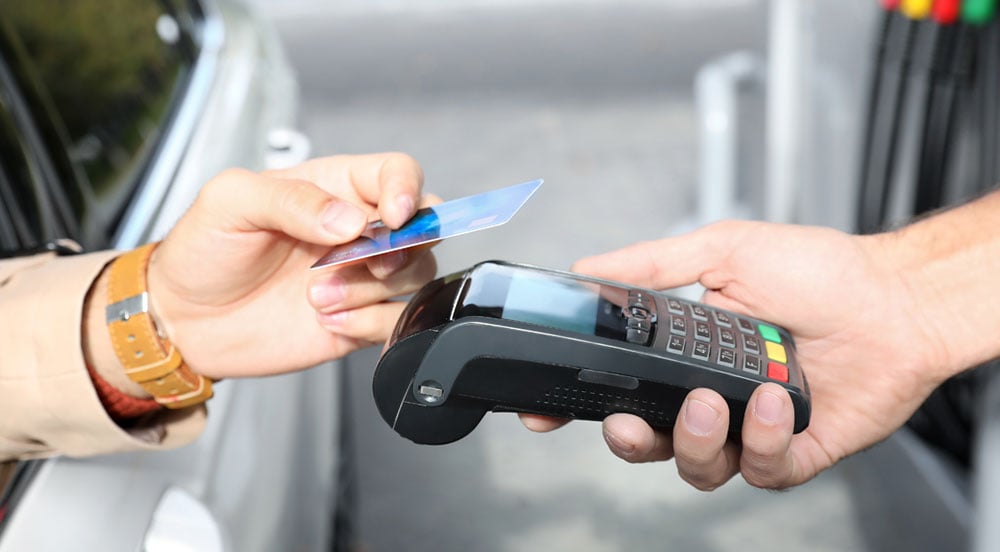 Sem Parar Empresas: pessoa em um carro com a mão para fora para pagar o abastecimento e suas compras no cartão combustível