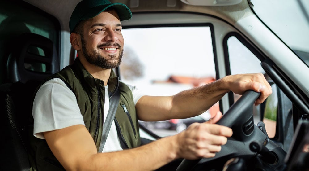 Motorista de caminhão sorrindo porque sabe sobre a ANTT: o que é com a Sem Parar Empresas