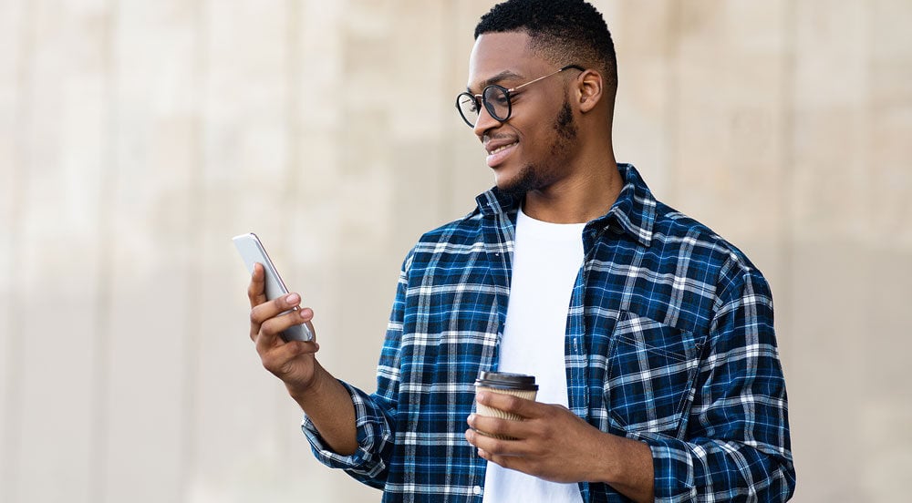 Sem Parar Empresas: homem com café e celular na mão para baixar documento do veículo