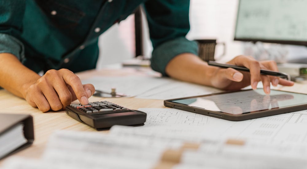 Sem Parar Empresas: pessoa utilizando calculadora e fazendo anotações em um tablet para entender como calcular vale-combustível para funcionário