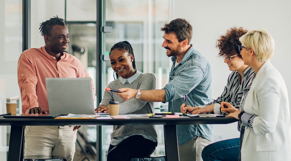 Sem Parar Empresas: Cinco pessoas reunidas em volta de uma mesa em um escritório para fazer a gestão de facilities