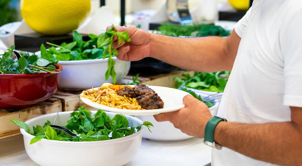 Homem se servindo de salada em um restaurante self-service que aceita o Vale-Refeição Sem Parar Empresas
