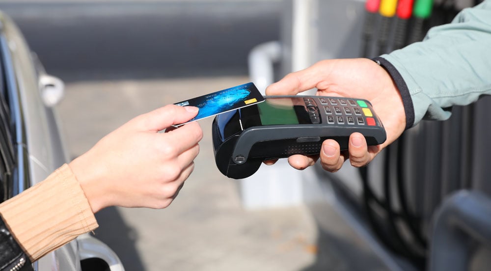 Sem Parar Empresas: mão saindo de um veículo aproximando o cartão combustível para frota de carros à maquininha que está na mão do frentista