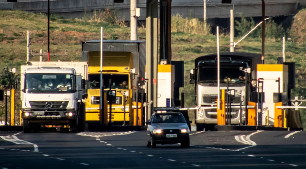 Praça de pedágio com carros e caminhões ilustrando gastos do vale-pedágio administrados pela solução da Sem Parar Empresas