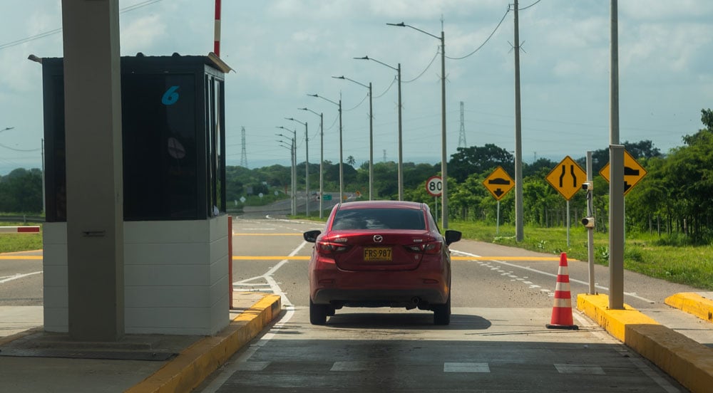 Praça de pedágio com um carro vermelho que usa a TAG Sem Parar para Empresas