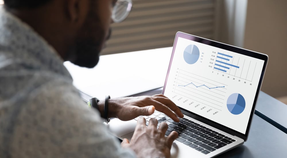 Homem olhando gráficos do relatório de consumo de combustível na tela do seu computador