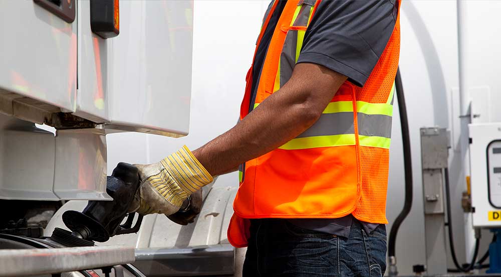 Frentista abastecendo um caminhão que recebe controle de combustível com soluções Sem Parar Empresas