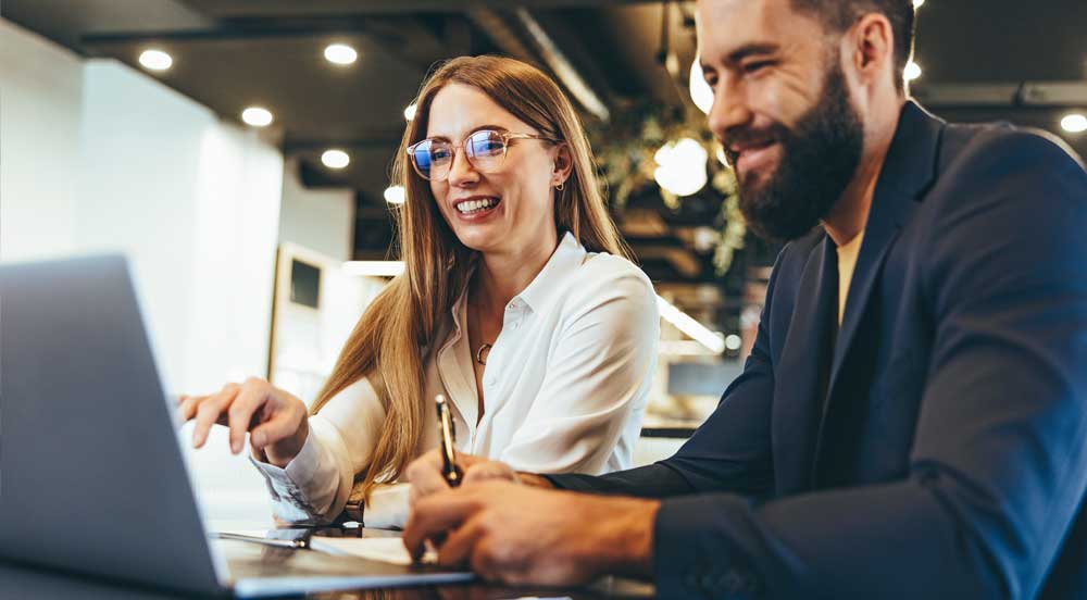 Homem e mulher olhando a tela do computador para avaliar os benefícios corporativos da Sem Parar Empresas