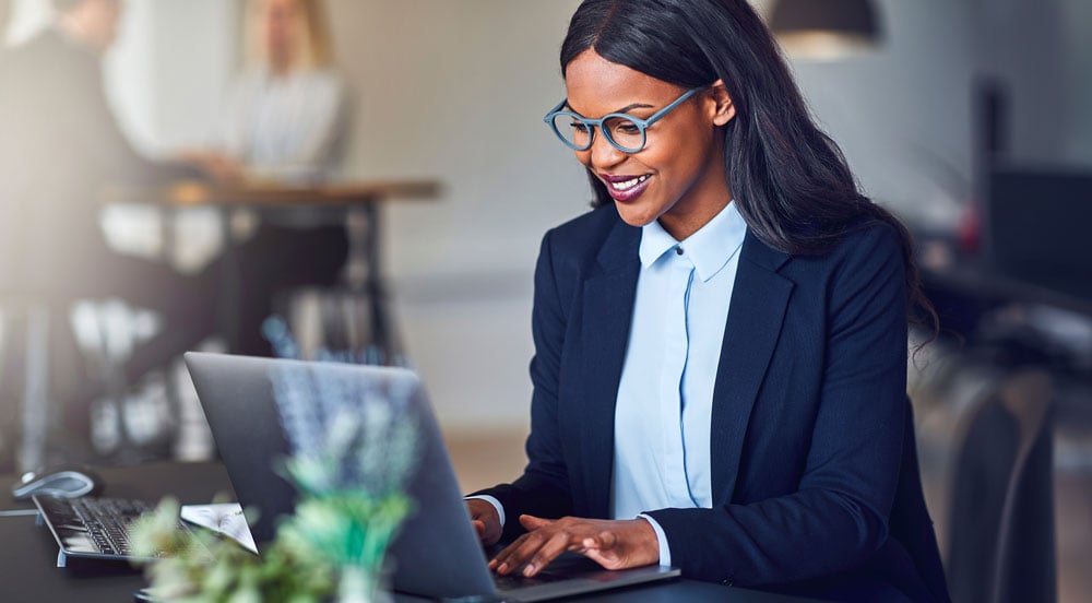 Mulher com um computador usando os benefícios da Sem Parar Empresas para auxílio com as funções do RH